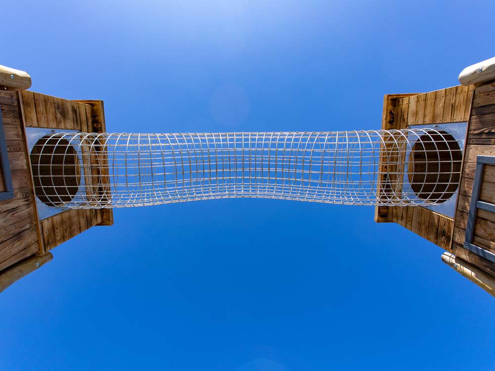 Der Gittertunnel des Kletterparcours von unten vor blauem Himmel