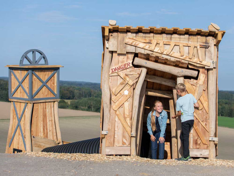 Mädchen und Junge kommen aus einem Tunnel des Kletter-Parcours