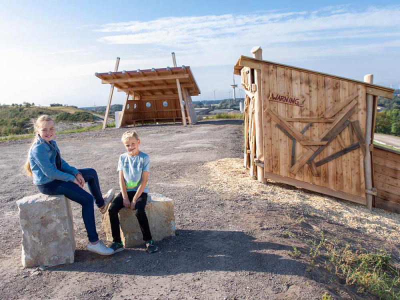 Mädchen und Junge sitzen auf Steinen auf dem Aussichtsplateau